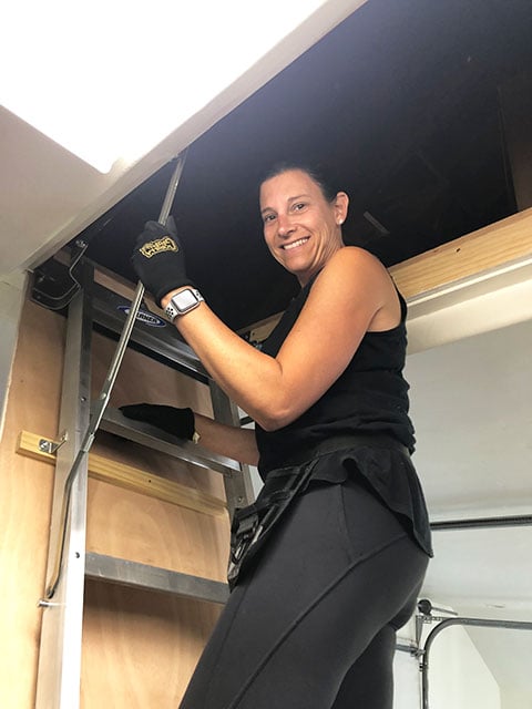 woman checking attic ladder and looking at camera